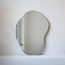 Modern freeform organic shaped mirror with a minimalist brass frame with a bronze patina finish