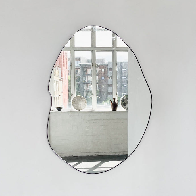 Modern freeform organic shaped mirror with a black powder coated aluminium frame