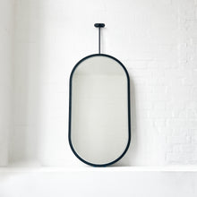 Modern front illuminated Capsula™ ceiling suspended pill shaped mirror with a black powder coated full frame