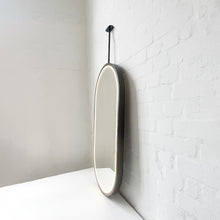 Modern front illuminated Capsula™ ceiling suspended pill shaped mirror with a black powder coated full frame.