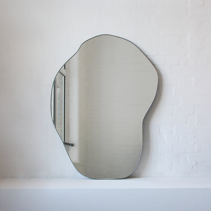 Modern freeform organic shaped mirror with a minimalist brass frame with a bronze patina finish
