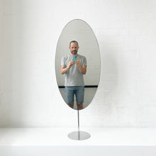 Countertop attached oval mirror with a modern stainless steel frame