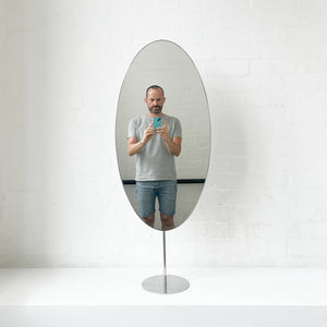 Countertop attached oval mirror with a modern stainless steel frame