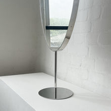 Countertop attached oval mirror with a modern stainless steel frame