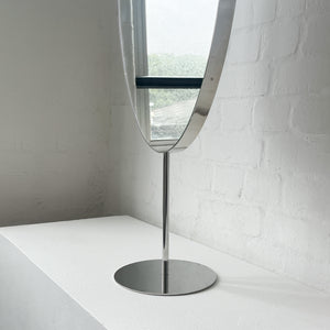 Countertop attached oval mirror with a modern stainless steel frame