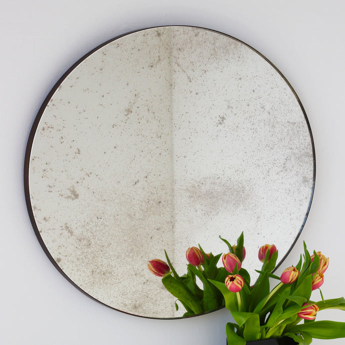 Antiqued round mirror with an elegant bronze patina brass frame